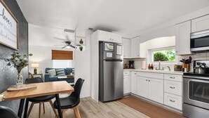 A modern kitchen with white cabinets, a stainless steel refrigerator, and a built-in oven. - Charlotte Chalet | Private Yard & Play Set (Sarasota)