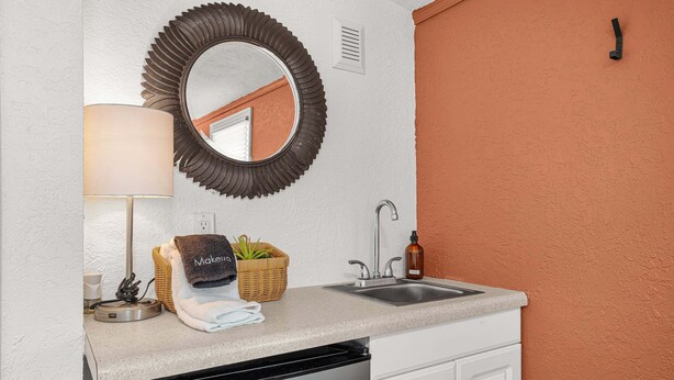 A bathroom with a sink, mirror, towel rack, and a small basket with towels. - Charlotte Chalet | Private Yard & Play Set (Sarasota)