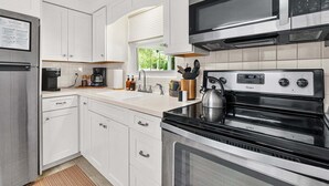 Une cuisine moderne avec des meubles blancs, un réfrigérateur en acier inoxydable, un four à micro-ondes et un four traditionnel.
