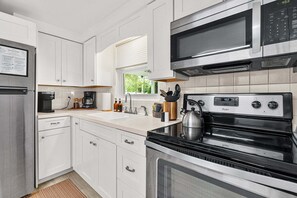 Eine moderne Küche mit weißen Schränken, einem Edelstahlkühlschrank, einer Mikrowelle und einem Backofen.