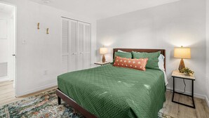 A bedroom with a bed, bedside lamps, a nightstand, a patterned rug, and a door with a closet. - Charlotte Chalet | Private Yard & Play Set (Sarasota)