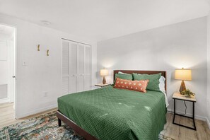 A bedroom with a bed, bedside lamps, a nightstand, a patterned rug, and a door with a closet. - Charlotte Chalet | Private Yard & Play Set (Sarasota)