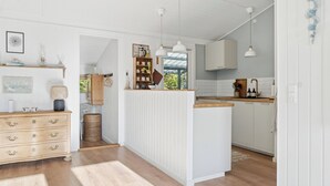 Una cucina moderna con mobili bianchi, piani in legno, luci a sospensione e un'isola centrale.