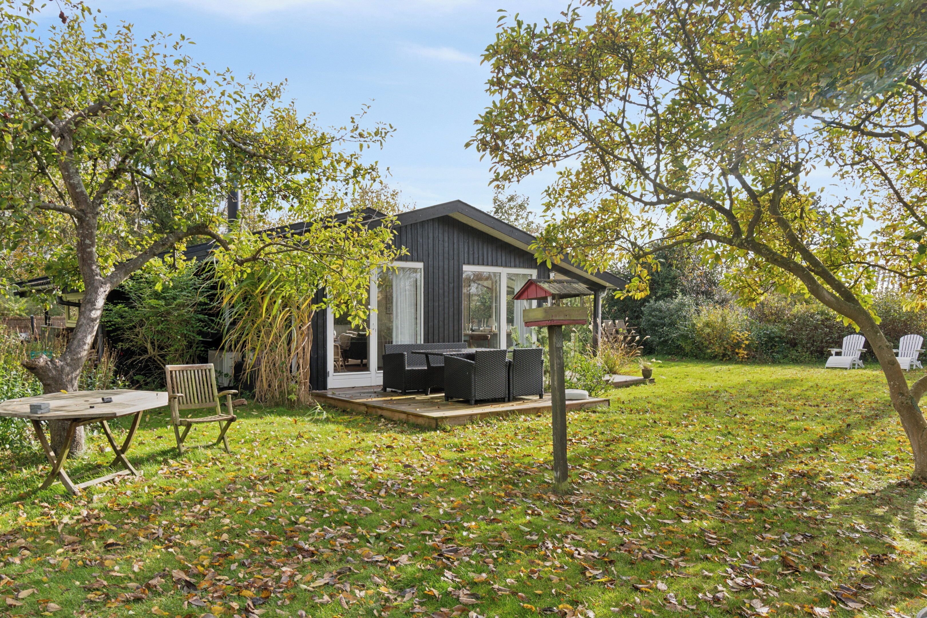 A modern house with a deck, outdoor furniture, and a garden.