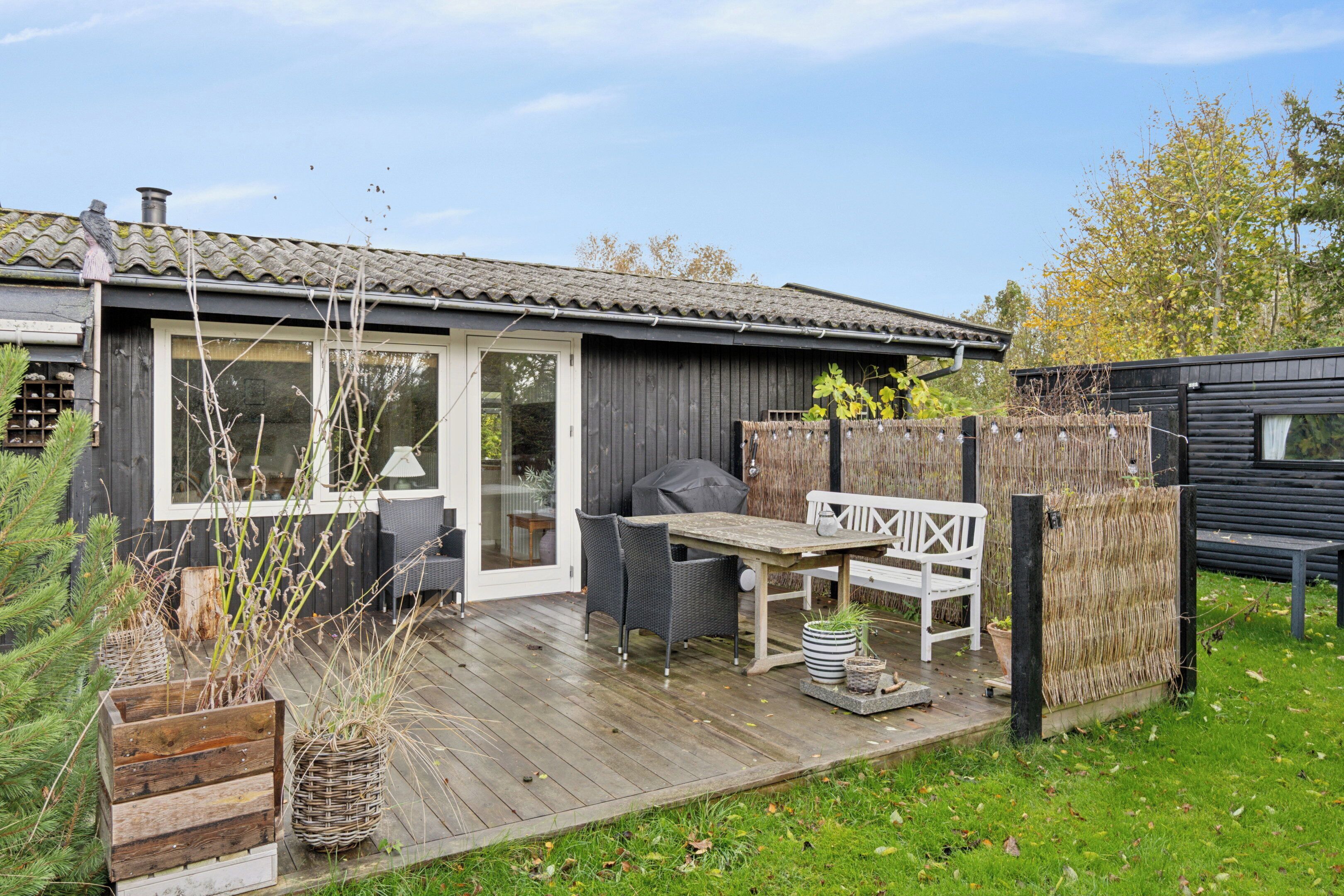 A wooden deck with outdoor furniture, a grill, and a wooden fence.