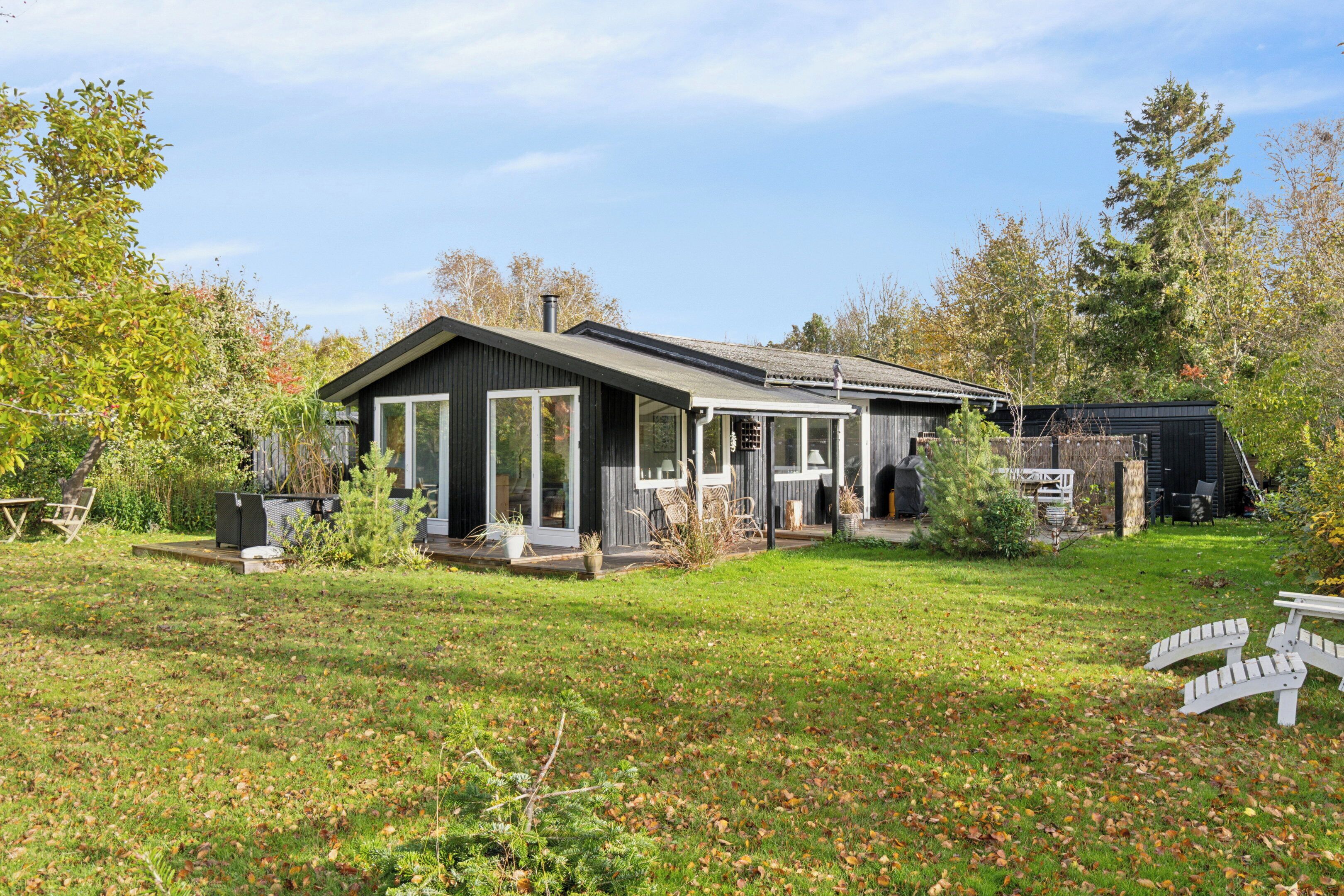 Een modern huis met een ruim terras, omringd door een verzorgd gazon en bomen.