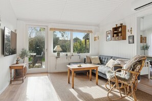 A room with a sofa, a rocking chair, a table, and a window. - Cozy holiday home by Kelstrup Beach (Slagelse)