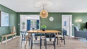 A modern living room with a wooden dining table, black chairs, a woven pendant light, and a grey sofa. - Olive Tree Oasis | 4/2 w/ Hot Tub + Heated Pool (Sarasota)