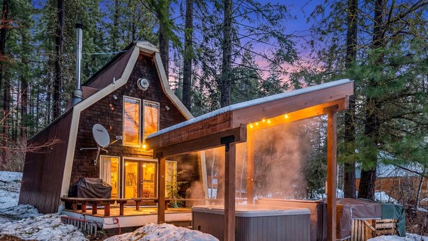 Eine Hütte mit Whirlpool, überdachter Veranda und Satellitenschüssel.