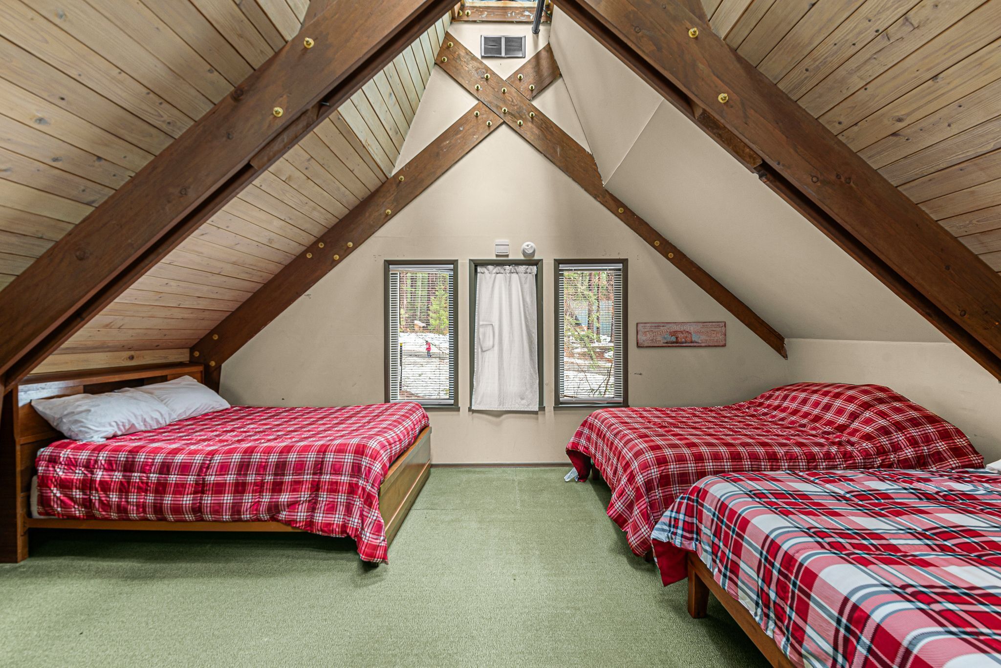 A small, cozy attic bedroom with two beds, wooden beams, and a sloped ceiling.