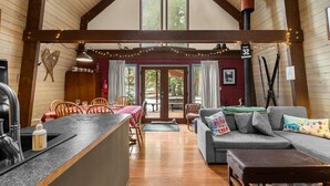 Ein gemütliches Blockhauskamin mit Essbereich, einer Couch und einer Küche.