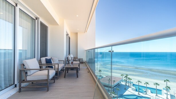 Ein Balkon mit Blick auf den Ozean, ausgestattet mit Stühlen und einem Tisch.