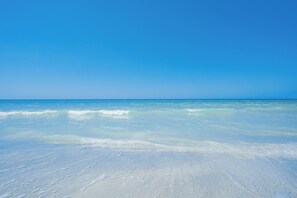 A beach with clear blue water and a sandy shore. - Sea Star Penthouse—Luxury Beachfront Escape w/ Private Elevator, Gulf Views & Designer Touches (Indian Shores)