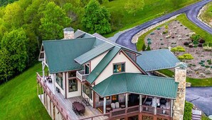 A large, two-story house with a green roof, a swimming pool, and a stone chimney. - Over The Top: Custom Luxury Home! Views, Hot Tub, Pool Table, Firepit, Claw Machine, More! (Banner Elk)