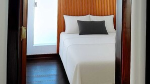 A modern bedroom with a wooden headboard, a white bed, and a dark wooden floor. - Best Location in Rio Vermelho, walking distance to the beach and fun (Salvador)