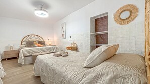 Un dormitorio con dos camas, una mesita de noche, un espejo en la pared y una lámpara en el techo.