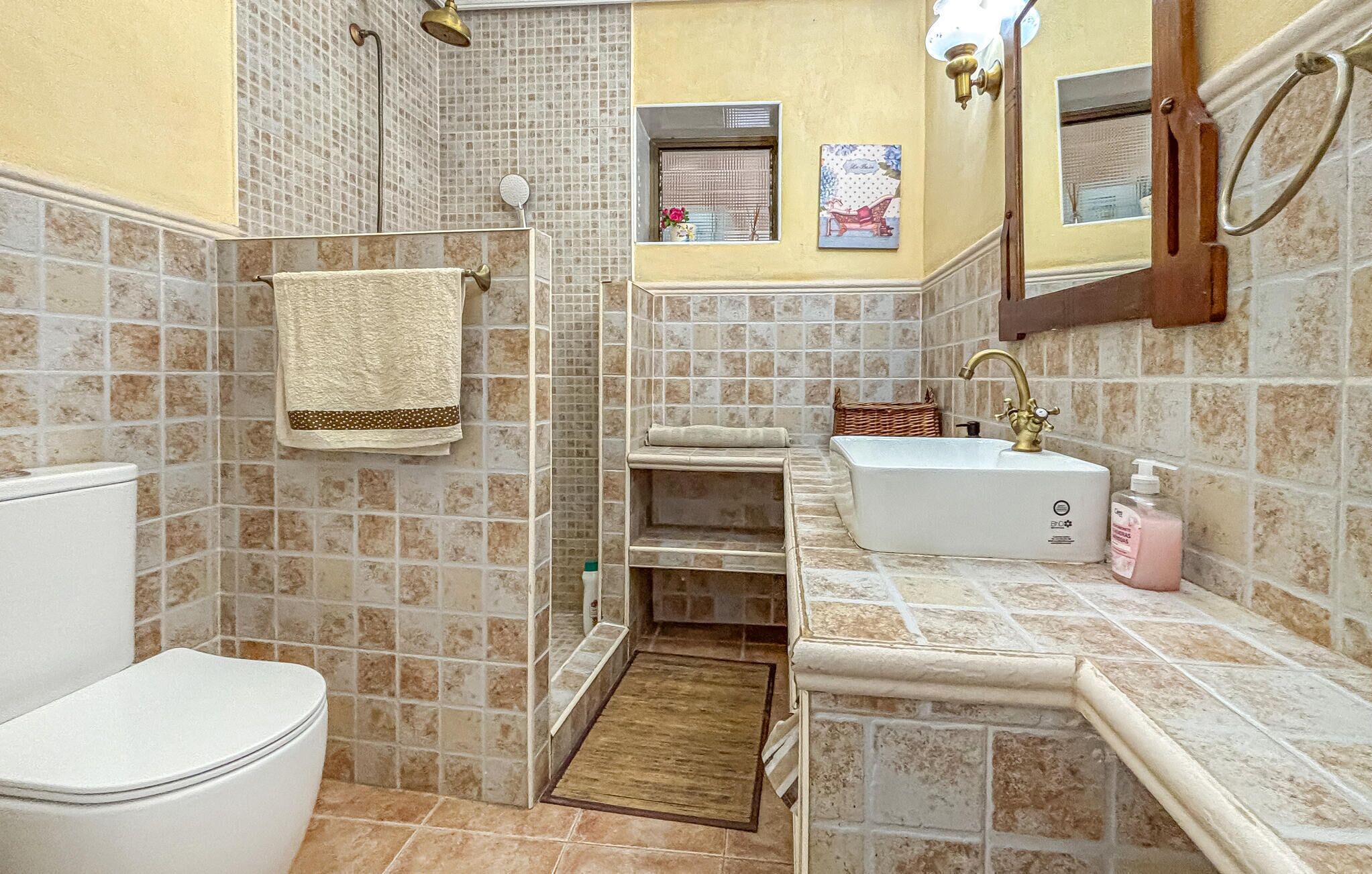 Ein Badezimmer mit Toilette, Dusche, Waschbecken und einem kleinen Fenster.