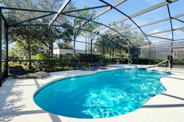 A swimming pool with a curved edge, surrounded by a covered area with a metal frame and glass panels. - The villa where dreams come true! (Davenport)