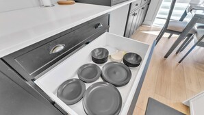 Un tiroir de cuisine contenant des assiettes et des bols soigneusement empilés.