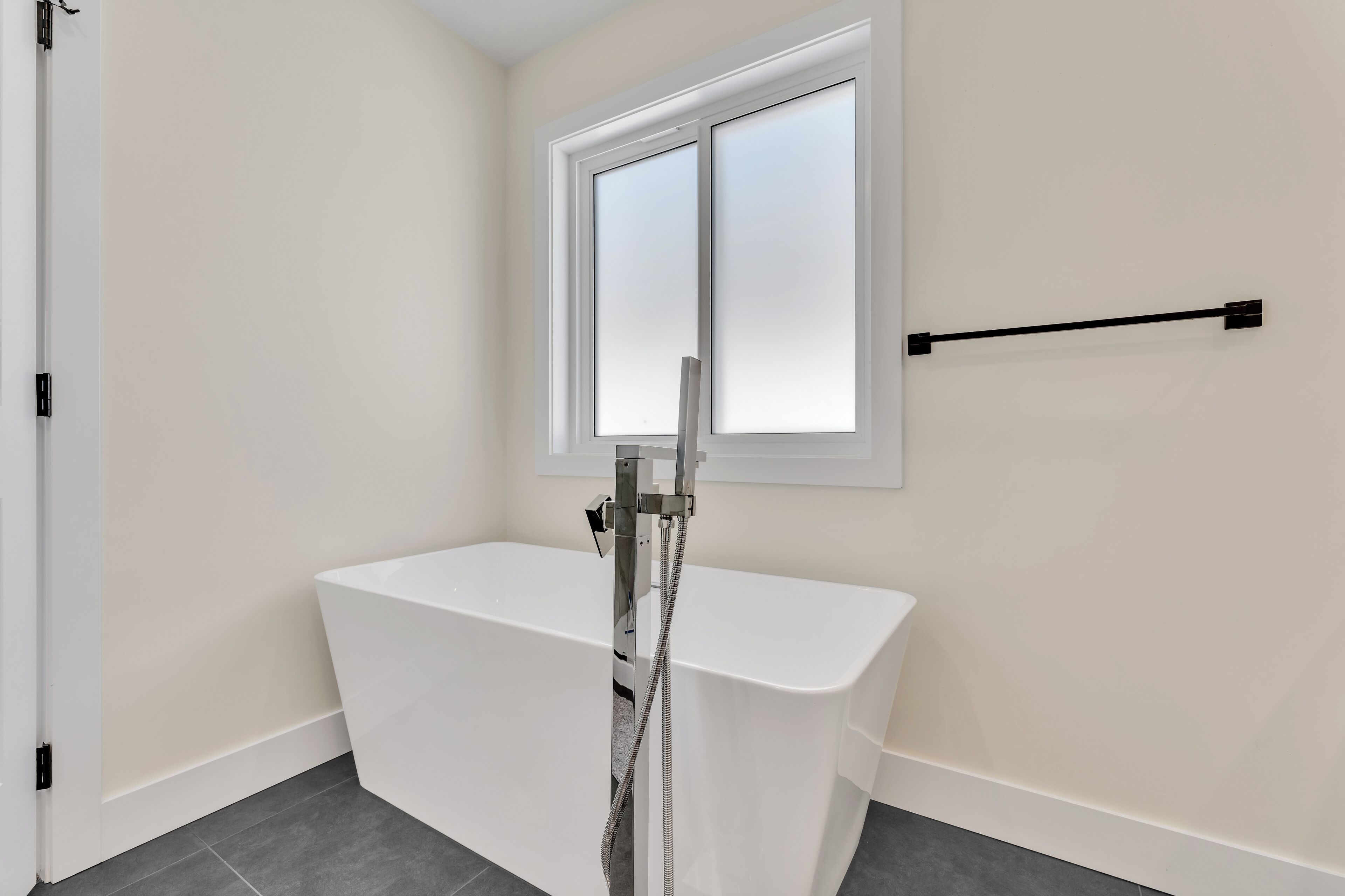 Une salle de bain avec une baignoire blanche, une fenêtre et un porte-serviettes.