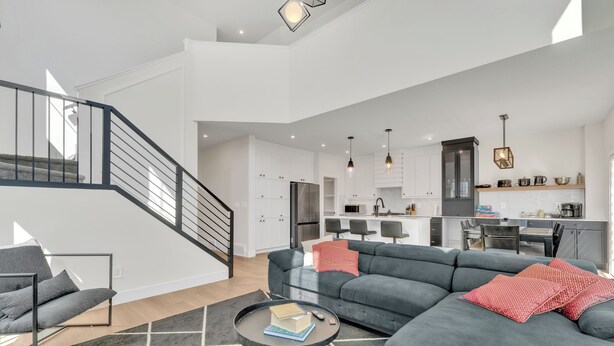 Un salon moderne avec un canapé d’angle gris, une table basse et un escalier menant à un niveau supérieur.