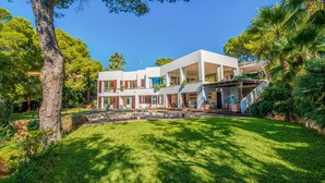 Ein modernes, zweistöckiges Haus mit Swimmingpool, umgeben von üppiger Vegetation und Palmen.