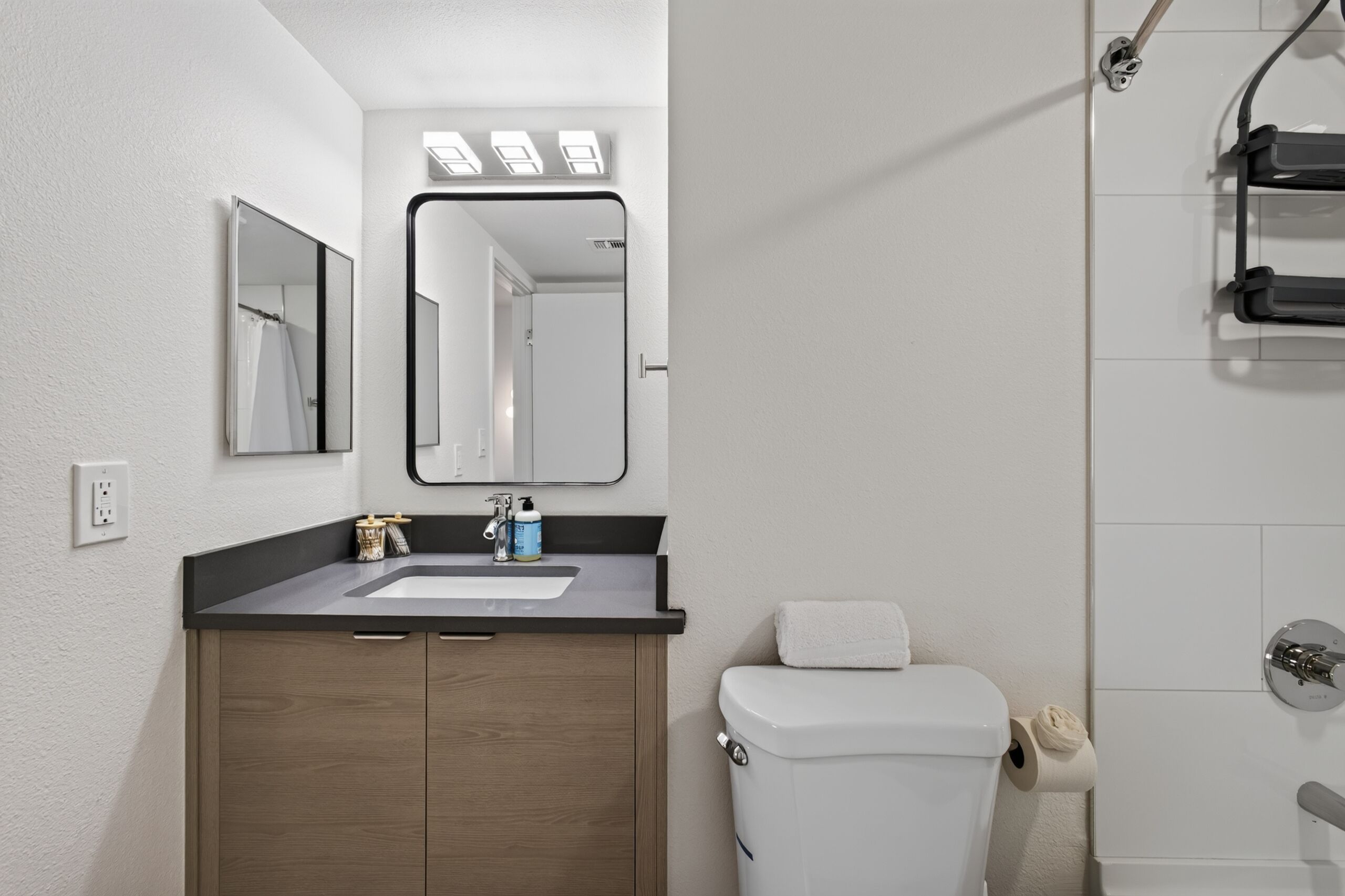 A modern bathroom with a sink, mirror, and toilet.