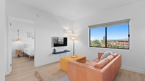 Una sala moderna con un sofá, un televisor y un ventanal con vistas a la ciudad.