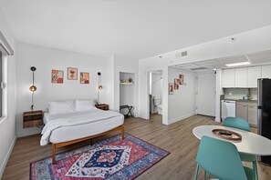 Quarto moderno com cama, tapete e escrivaninha com cadeiras.