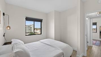 Une chambre à coucher avec un lit, une fenêtre et une vue sur les bâtiments environnants.