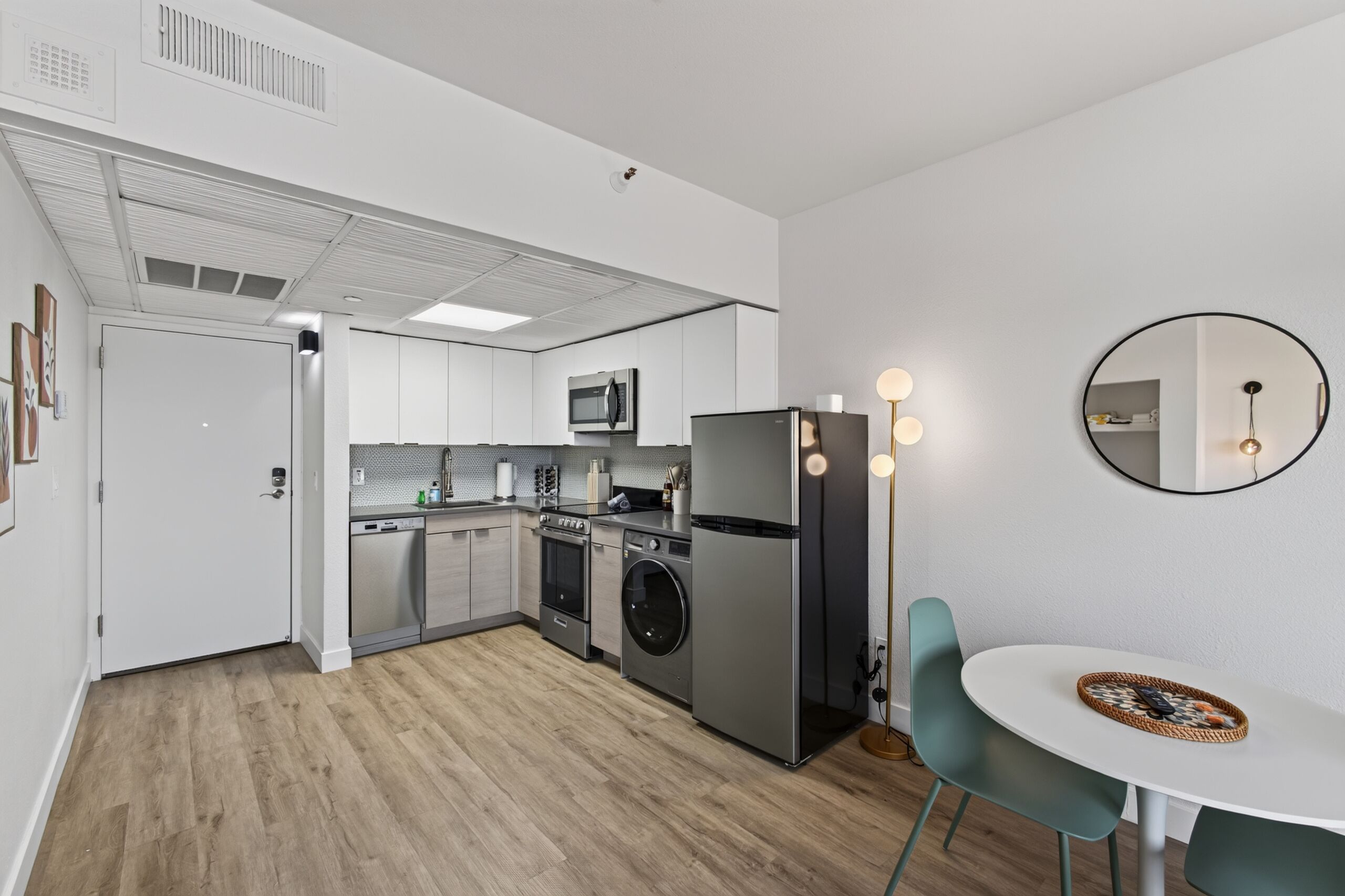 Una cucina moderna con elettrodomestici in acciaio inossidabile, una lavatrice e un'area pranzo con un tavolo rotondo e sedie.
