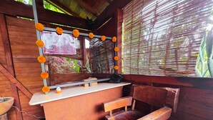 A wooden bar area with a counter, a chair, and a window with bamboo blinds. - Cabañas El nido de la Huilota (Tepoztlan)