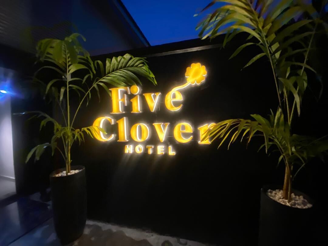 A hotel sign with the name "Five Clover Hotel" illuminated in yellow.