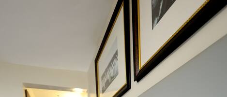 A hotel room with a neatly made bed, a headboard, and framed pictures on the wall.