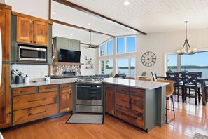 Une cuisine moderne avec des meubles en bois, un four à micro-ondes encastré, une grande cuisinière et un coin repas offrant une vue agréable.