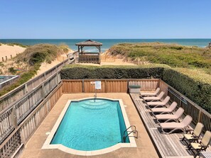 A pool with a wooden deck, lounge chairs, and a gazebo overlooking a beach. - Shore Beats Work: Oceanfront Views, Pool, Hot Tub, Sauna, Discounted Golf Rates (Nags Head)