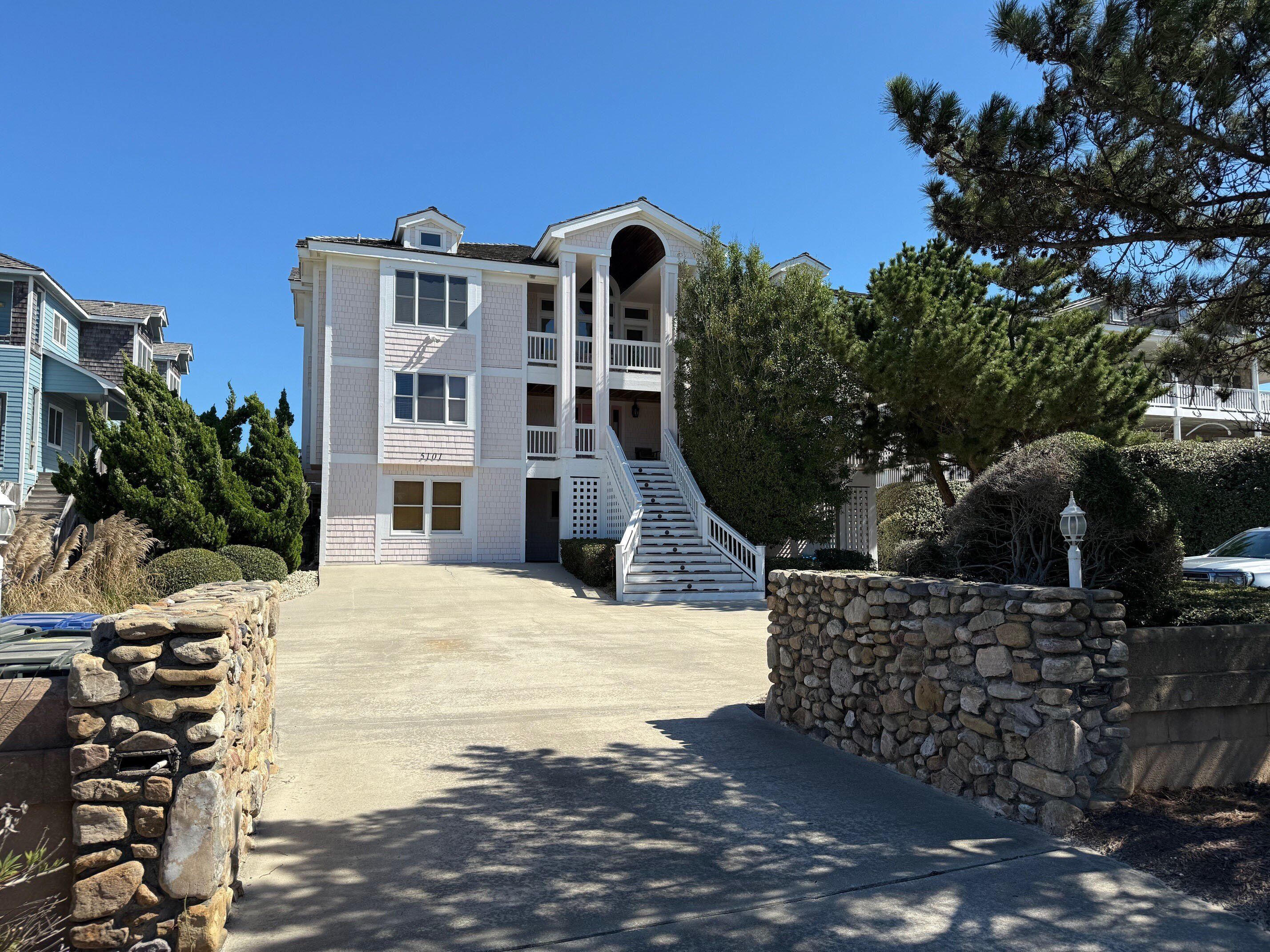 Un edificio residencial de varios pisos con una escalera central, paredes de piedra y vegetación circundante.