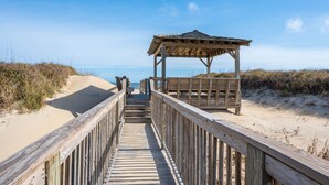 Una pasarela de madera que conduce a una playa, con una estructura de madera y bancos.