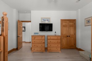 A room with a TV mounted on the wall, wooden cabinets, and a door. - 16 Sunset: Private Pool, Hot Tub, Game Room, Community Amenities (Corolla)