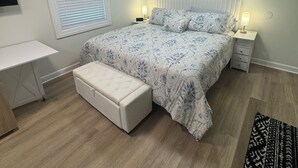A bedroom with a bed, bedside tables, a desk, a bench, and an air conditioning unit. - Charming & luxurious 1-bedroom condo, Kitchen, Washer, dryer, parking, King Bed. (Hagerstown)