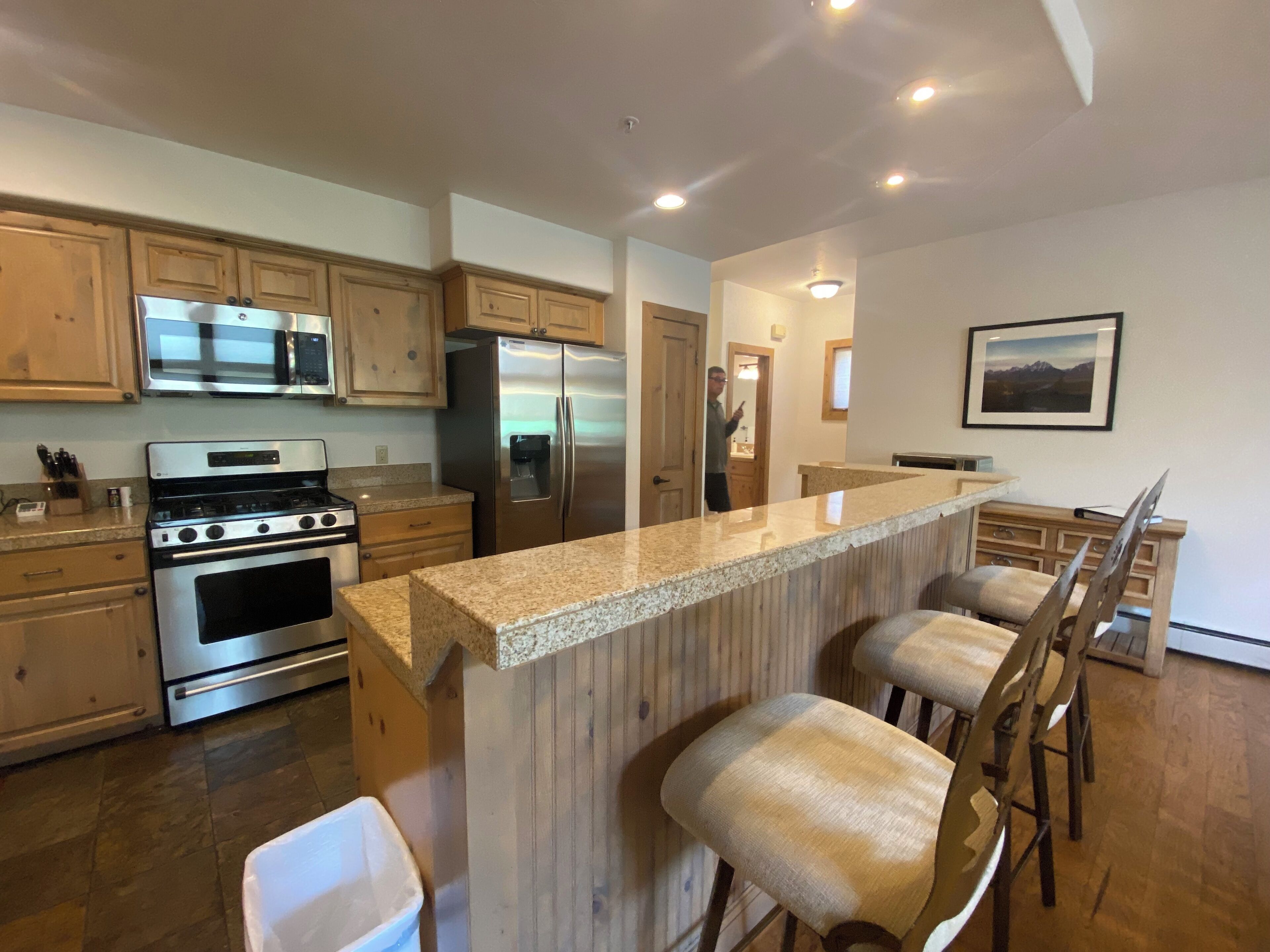 A modern kitchen with stainless steel appliances, wooden cabinets, and a granite countertop.