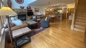 Una sala de estar amplia con chimenea, asientos cómodos, comedor y cocina.