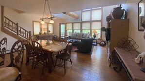 Un amplio espacio de sala con una mesa de comedor, sillas, un sofá y un ventanal grande.