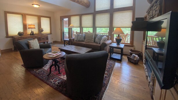 Un salón amplio con un gran ventanal, una chimenea y un televisor.