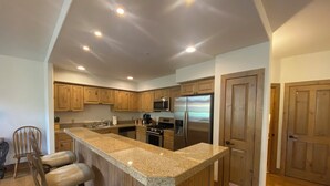 Una cocina con gabinetes de madera, un refrigerador de acero inoxidable, un microondas y una encimera de granito.