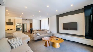 A modern living room with a sofa, two coffee tables, and a TV mounted on the wall. - Stylish Villa with Private Pool & Sea Views (Kalkan)