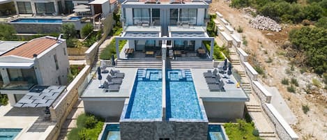 Un resort moderno con una piscina central, varios balcones y vistas del paisaje circundante.
