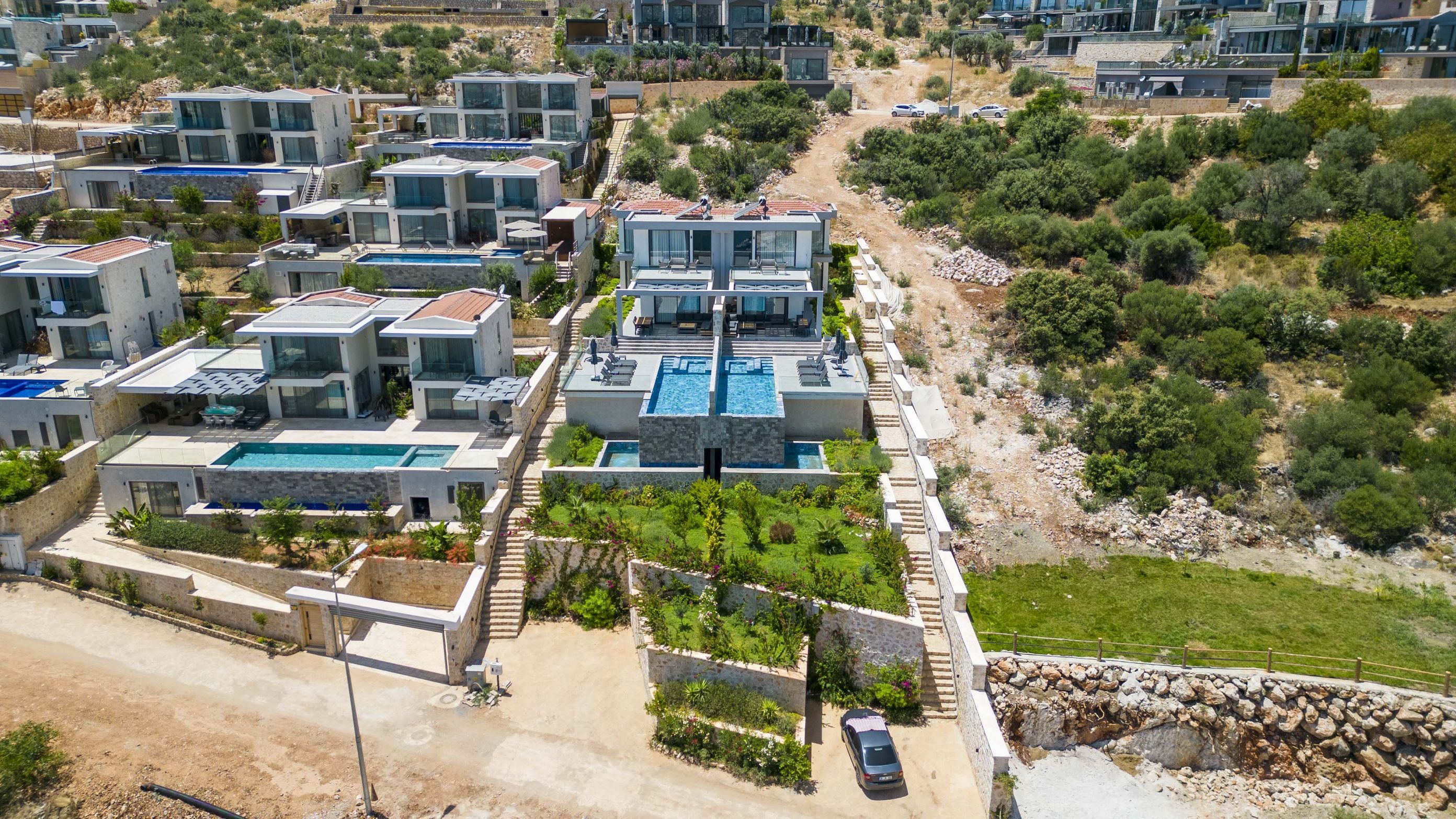 Un complesso residenziale moderno con diversi edifici a due piani, una piscina centrale e aree verdi circostanti.