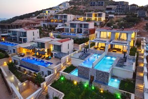 A modern resort with multiple swimming pools and outdoor seating areas. - Stylish Villa with Private Pool & Sea Views (Kalkan)