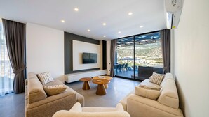 A modern living room with a sofa set, a coffee table, and a flat-screen TV mounted on the wall. - Stylish Villa with Private Pool & Sea Views (Kalkan)